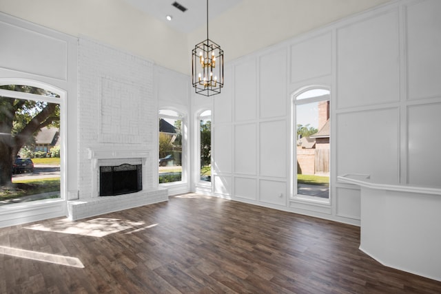 unfurnished living room with a fireplace, a high ceiling, plenty of natural light, and dark hardwood / wood-style flooring