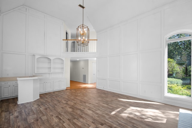 unfurnished living room featuring dark hardwood / wood-style floors, a healthy amount of sunlight, and an inviting chandelier