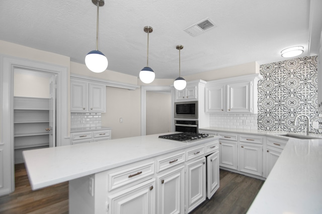 kitchen with white cabinetry, sink, appliances with stainless steel finishes, tasteful backsplash, and hanging light fixtures