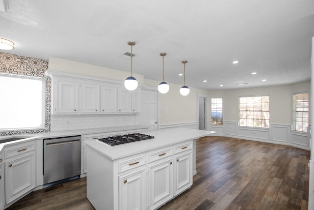 kitchen with stainless steel appliances, white cabinetry, hanging light fixtures, a center island, and dark hardwood / wood-style flooring