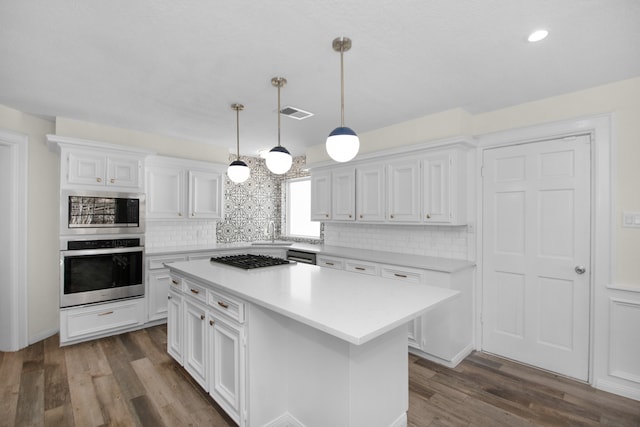 kitchen with stainless steel appliances, white cabinetry, decorative light fixtures, dark wood-type flooring, and a center island