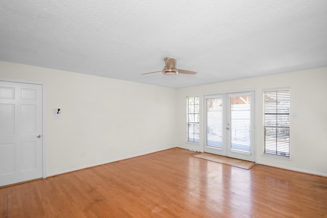 empty room featuring a textured ceiling, light wood-type flooring, ceiling fan, and french doors