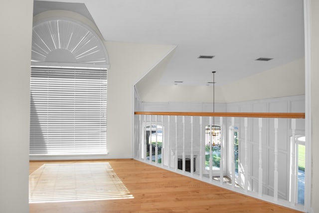 corridor with hardwood / wood-style floors, a notable chandelier, and lofted ceiling