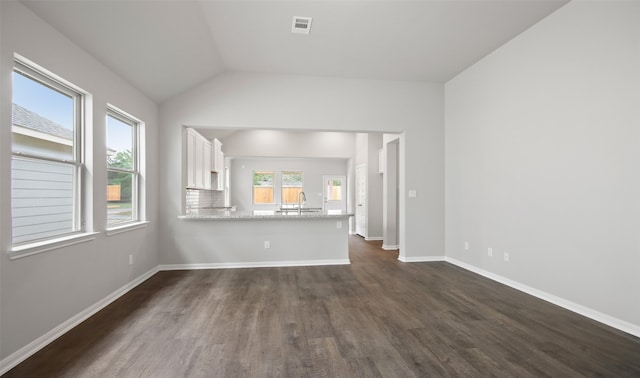 unfurnished living room featuring dark wood-type flooring, sink, and vaulted ceiling