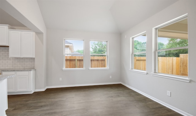 unfurnished dining area featuring lofted ceiling and dark hardwood / wood-style floors