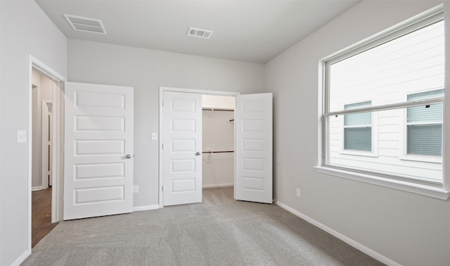 unfurnished bedroom featuring light colored carpet, a spacious closet, and a closet