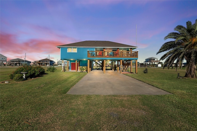 back house at dusk featuring a carport and a lawn