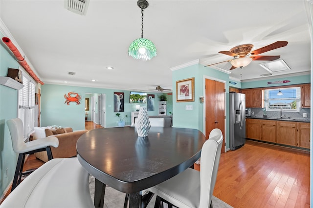 dining space with light hardwood / wood-style floors, ornamental molding, and sink