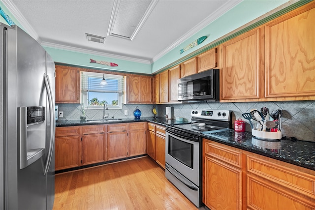 kitchen with appliances with stainless steel finishes, tasteful backsplash, crown molding, sink, and light hardwood / wood-style floors