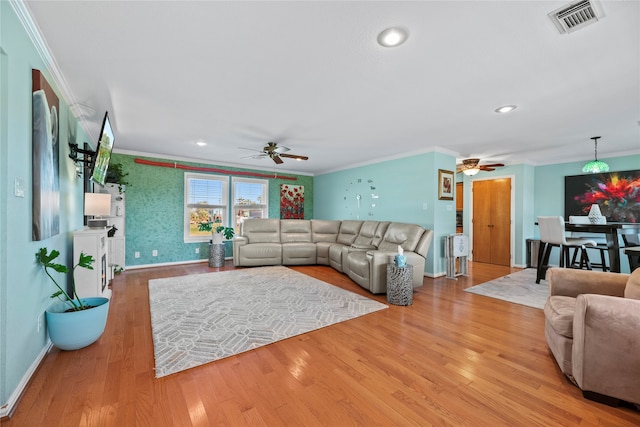 living room featuring crown molding, ceiling fan, and light wood-type flooring