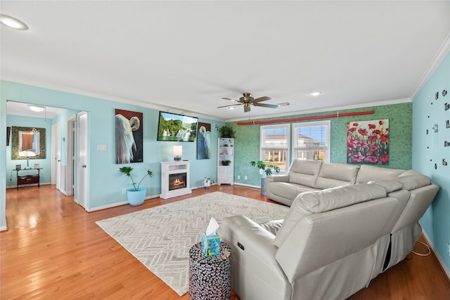 living room featuring hardwood / wood-style flooring, ceiling fan, and ornamental molding