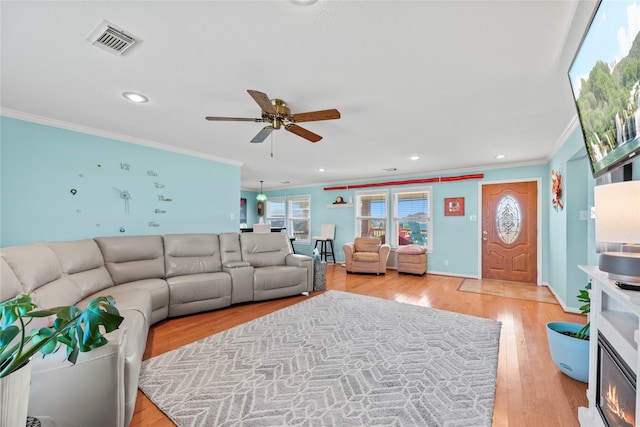 living room with ceiling fan, light wood-type flooring, and crown molding