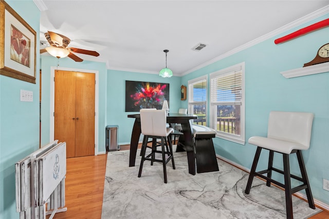 dining room with hardwood / wood-style flooring, ceiling fan, and crown molding