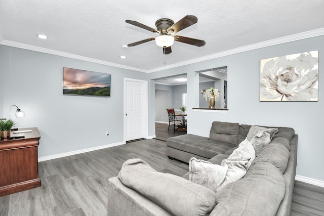 living room featuring ceiling fan, a textured ceiling, ornamental molding, and hardwood / wood-style floors