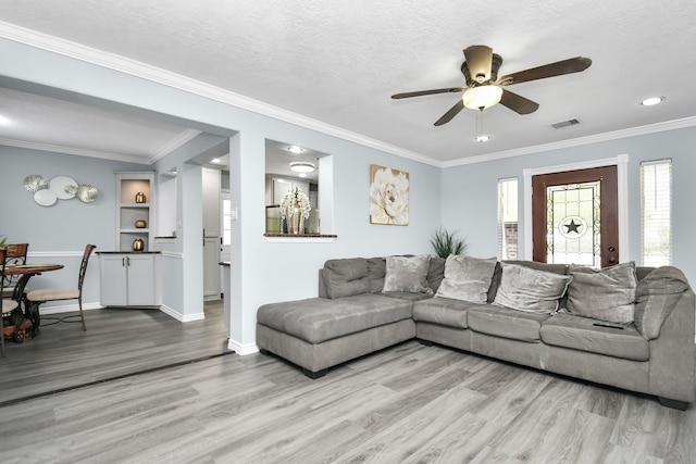 living room with a textured ceiling, ceiling fan, ornamental molding, and light hardwood / wood-style floors