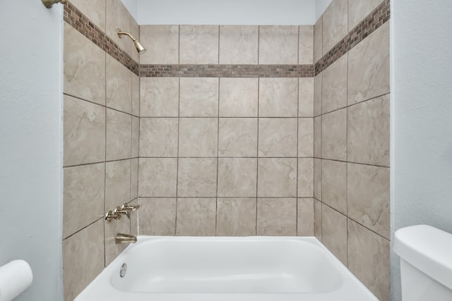 bathroom featuring toilet and tiled shower / bath combo