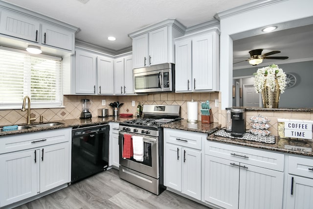 kitchen with stainless steel appliances, tasteful backsplash, dark stone countertops, sink, and ornamental molding