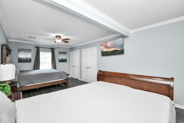 bedroom featuring ceiling fan, dark hardwood / wood-style floors, ornamental molding, and two closets