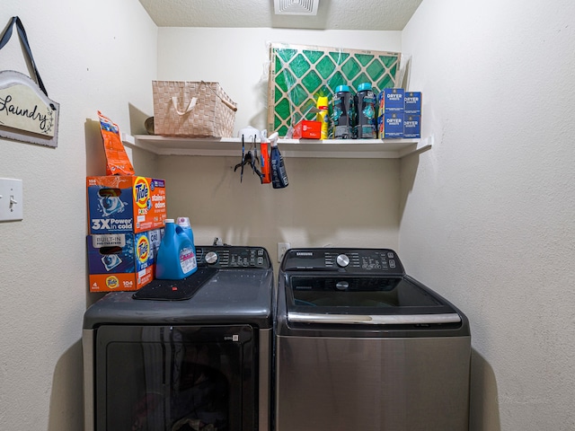 laundry area with a textured ceiling and separate washer and dryer