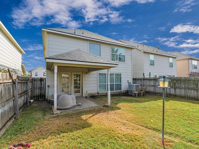 back of property with cooling unit, a yard, and a patio area