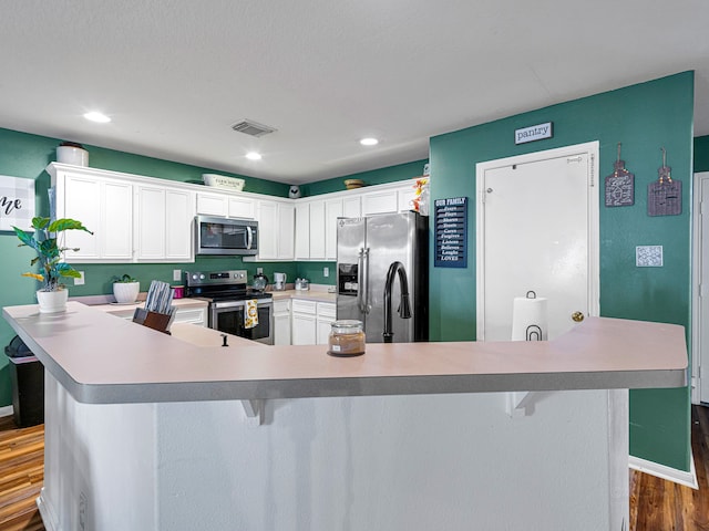 kitchen featuring stainless steel appliances, white cabinetry, a breakfast bar area, a spacious island, and dark hardwood / wood-style flooring