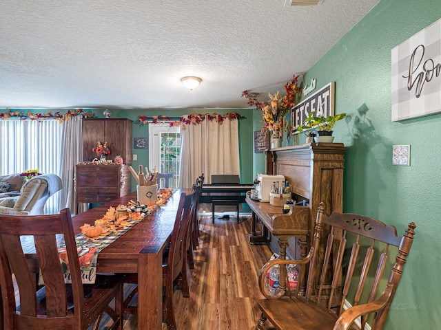 dining room featuring dark hardwood / wood-style flooring and a textured ceiling