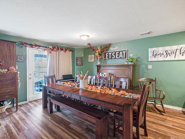 dining room featuring wood-type flooring and a textured ceiling