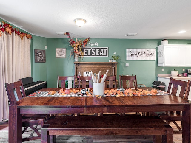 dining area with wood-type flooring and a textured ceiling