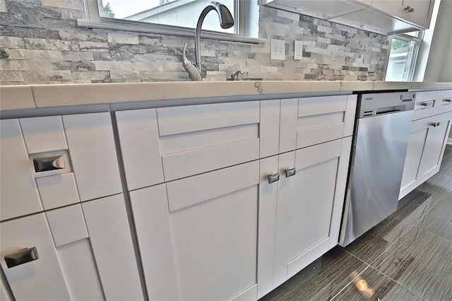 kitchen featuring white cabinetry, stainless steel dishwasher, and backsplash