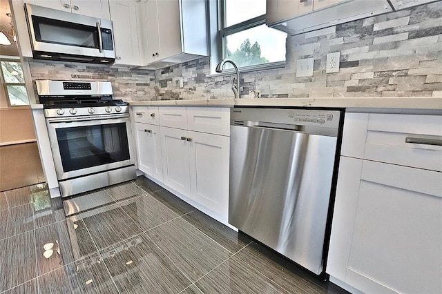 kitchen with dark tile patterned flooring, white cabinetry, appliances with stainless steel finishes, and tasteful backsplash