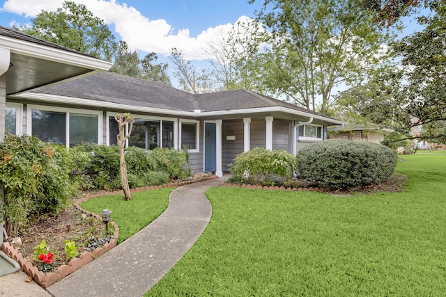 view of front of house with a shingled roof and a front yard