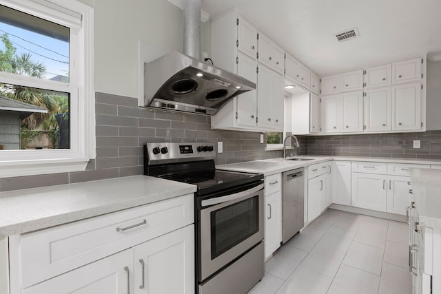 kitchen featuring range hood, a healthy amount of sunlight, stainless steel appliances, and white cabinets