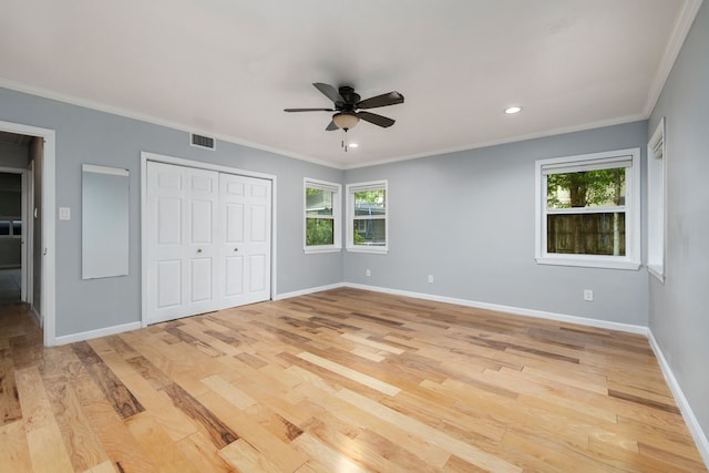 unfurnished bedroom featuring multiple windows, ornamental molding, and light wood-type flooring