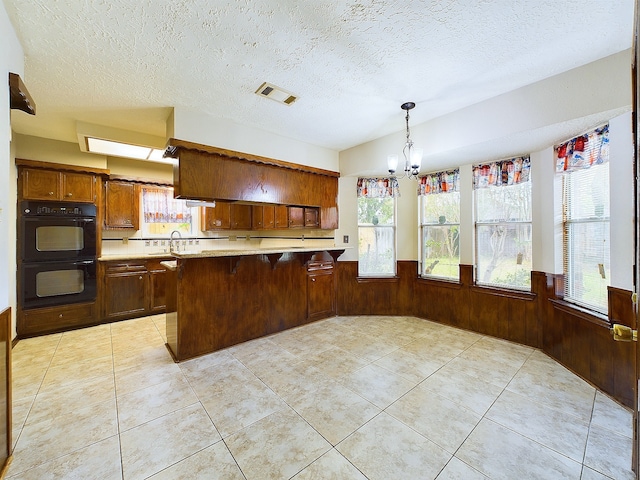 kitchen featuring wooden walls, a textured ceiling, and kitchen peninsula