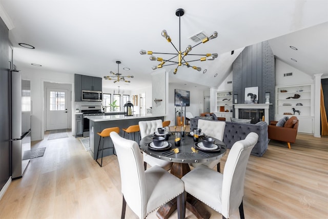 dining room featuring light hardwood / wood-style floors, built in features, a fireplace, and a chandelier