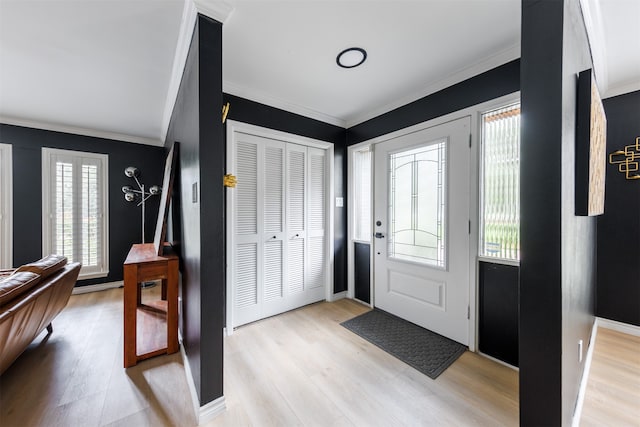 foyer entrance with light hardwood / wood-style floors, ornamental molding, and a wealth of natural light