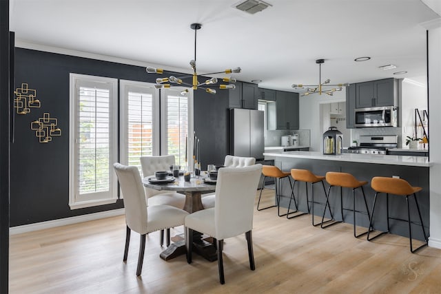 dining area featuring light hardwood / wood-style floors, crown molding, and a chandelier