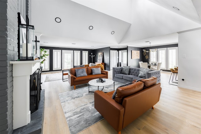 living room with a fireplace, vaulted ceiling, and light wood-type flooring