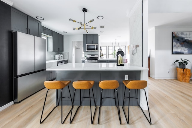 kitchen with pendant lighting, a center island, tasteful backsplash, a notable chandelier, and stainless steel appliances