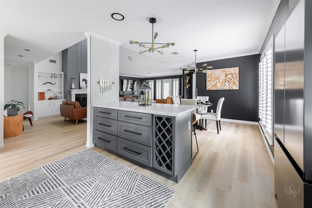 kitchen featuring a large fireplace, hanging light fixtures, a notable chandelier, kitchen peninsula, and gray cabinets