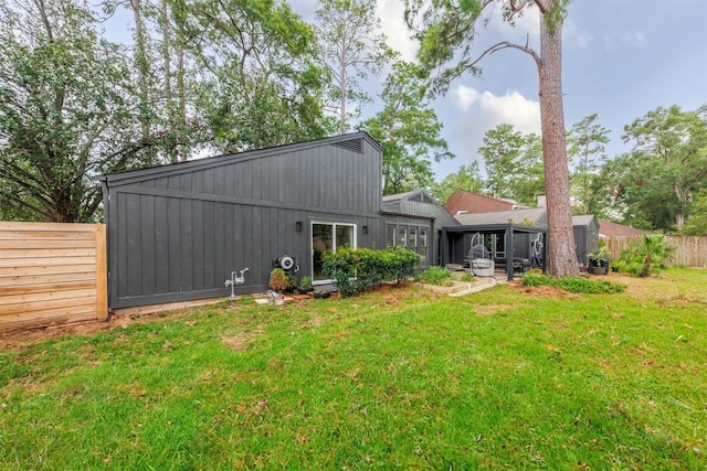 back of property featuring a sunroom and a lawn