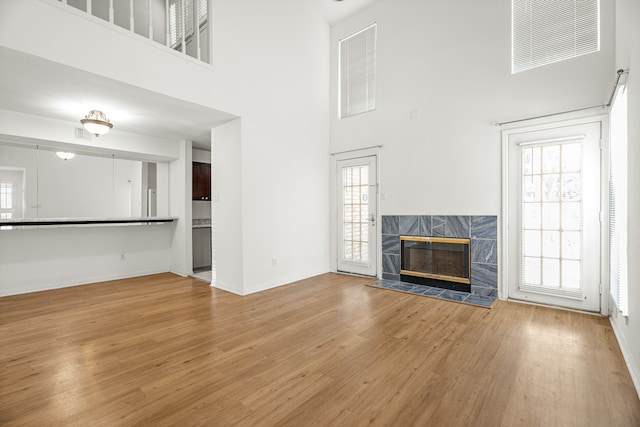 unfurnished living room featuring a fireplace, a high ceiling, and light hardwood / wood-style flooring