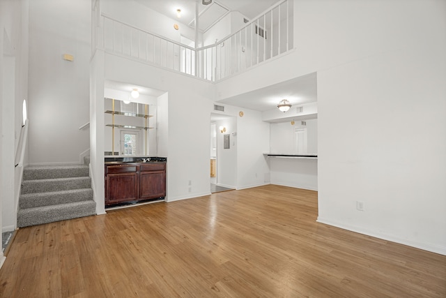 unfurnished living room with light hardwood / wood-style flooring and a high ceiling