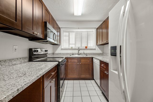 kitchen featuring sink, light stone counters, a textured ceiling, white appliances, and light tile patterned floors