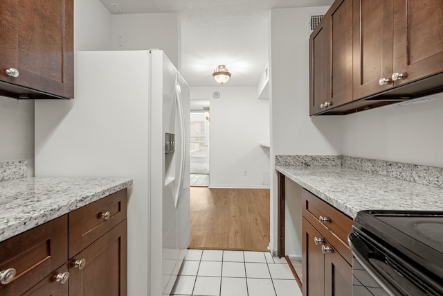 kitchen with white fridge with ice dispenser, light stone countertops, and light hardwood / wood-style flooring