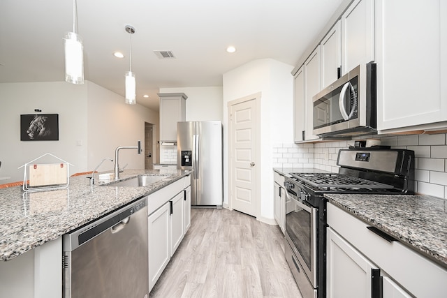 kitchen with light hardwood / wood-style floors, stainless steel appliances, sink, light stone countertops, and white cabinetry