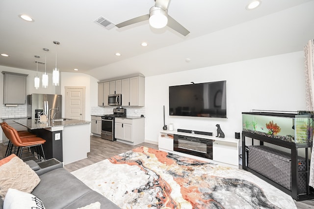 living room featuring light hardwood / wood-style floors, ceiling fan, and sink