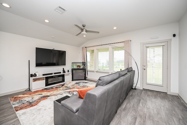 living room featuring a fireplace, light hardwood / wood-style flooring, lofted ceiling, and ceiling fan