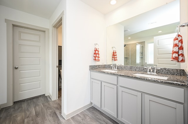 bathroom with hardwood / wood-style flooring, a shower with door, and vanity