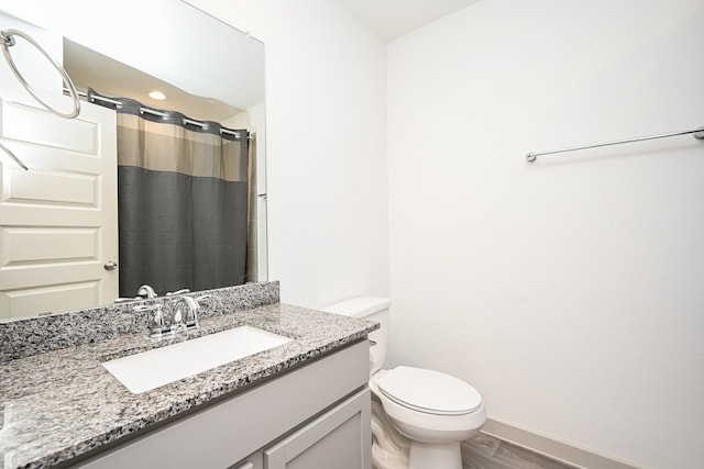 bathroom featuring hardwood / wood-style floors, walk in shower, vanity, and toilet